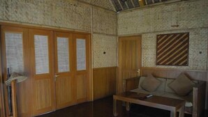 A room with wooden doors, a sofa, a table, and a lamp. - Kampung Sampireun Resort And Spa (Samarang)