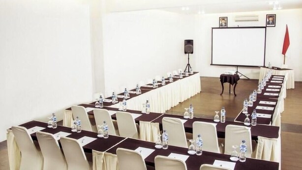 A conference room with long tables, chairs, and a projector screen. - Kampung Sampireun Resort And Spa (Samarang)
