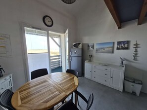 A compact kitchen with a wooden dining table, white cabinets, a refrigerator, and a clock on the wall. - Charming apartment ideal for 4 people, perfect for a comfortable stay between ocean and... (BISCARROSSE PLAGE)