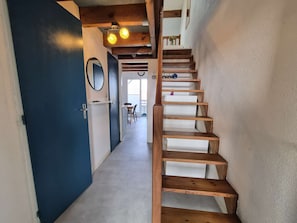 A wooden staircase leading to a landing with a white door and a mirror on the wall. - Charming apartment ideal for 4 people, perfect for a comfortable stay between ocean and... (BISCARROSSE PLAGE)
