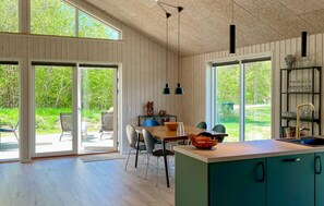 A modern kitchen with a large island, sliding glass doors to a patio, and a view of greenery. - 3 bedroom nice home in Rørvig (Rørvig)