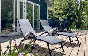A deck with two lounge chairs, a table, and chairs, overlooking a garden. - 3 bedroom nice home in Rørvig (Rørvig)