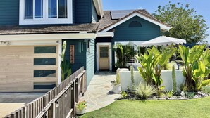 Ein zweistöckiges Haus mit Garage, überdachter Terrasse und gepflegtem Garten mit verschiedenen Pflanzen.