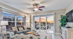 A spacious living room with a sofa, coffee table, and a ceiling fan. - Spacious Upscale 3BR Condo Balcony Ocean View & Steps to Beach (Daytona Beach)