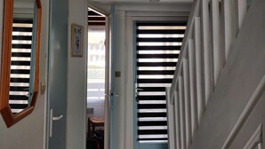 Ein Korridor mit Deckenleuchte, einem spiegelnden Holzboden und einer Tür zu einem weiteren Raum.