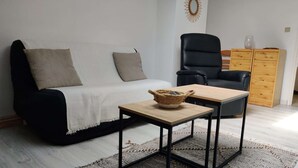 Ein Wohnzimmer mit einer Couch, einem Sessel, einem kleinen Tisch und einem Holzschrank.