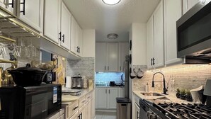 A modern kitchen with white cabinetry, a stainless steel stove, and a microwave.