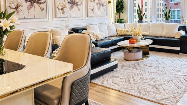 A modern living room with a sofa, chairs, a dining table, and artwork on the wall.