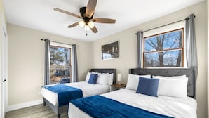 A hotel room with two beds, a ceiling fan, large windows, and a view of the outdoors. - Finally… A Home Big Enough for Everyone 8 Beds (Woodstock)