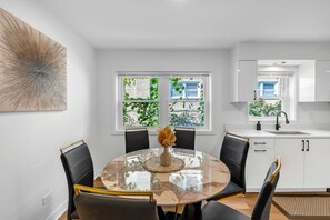 A modern kitchen with white cabinets, a round marble table, and black chairs. - Spacious Westchester Duplex for Group & Family (Westchester)