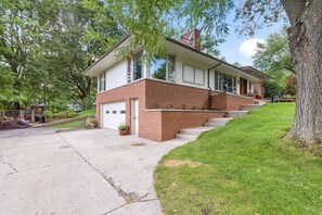 A two-story house with a garage, a front yard with a tree, and a driveway. - Spacious 4BR Retreat in Rockford (Rockford)