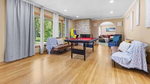 Een ruime kamer met een pooltafel, een bank en een open haard.