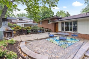 A backyard with a brick patio, a barbecue grill, and a dining area with a table and chairs. - Spacious 4BR Retreat in Rockford (Rockford)