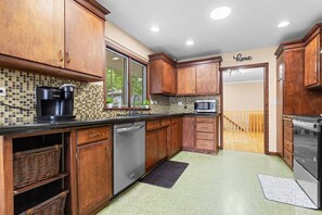 A kitchen with wooden cabinets, a dishwasher, a coffee maker, and a microwave. - Spacious 4BR Retreat in Rockford (Rockford)