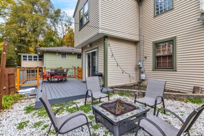 Eine Terrasse mit Gartenmöbeln, einem Feuerkorb und einem überdachten Patio.