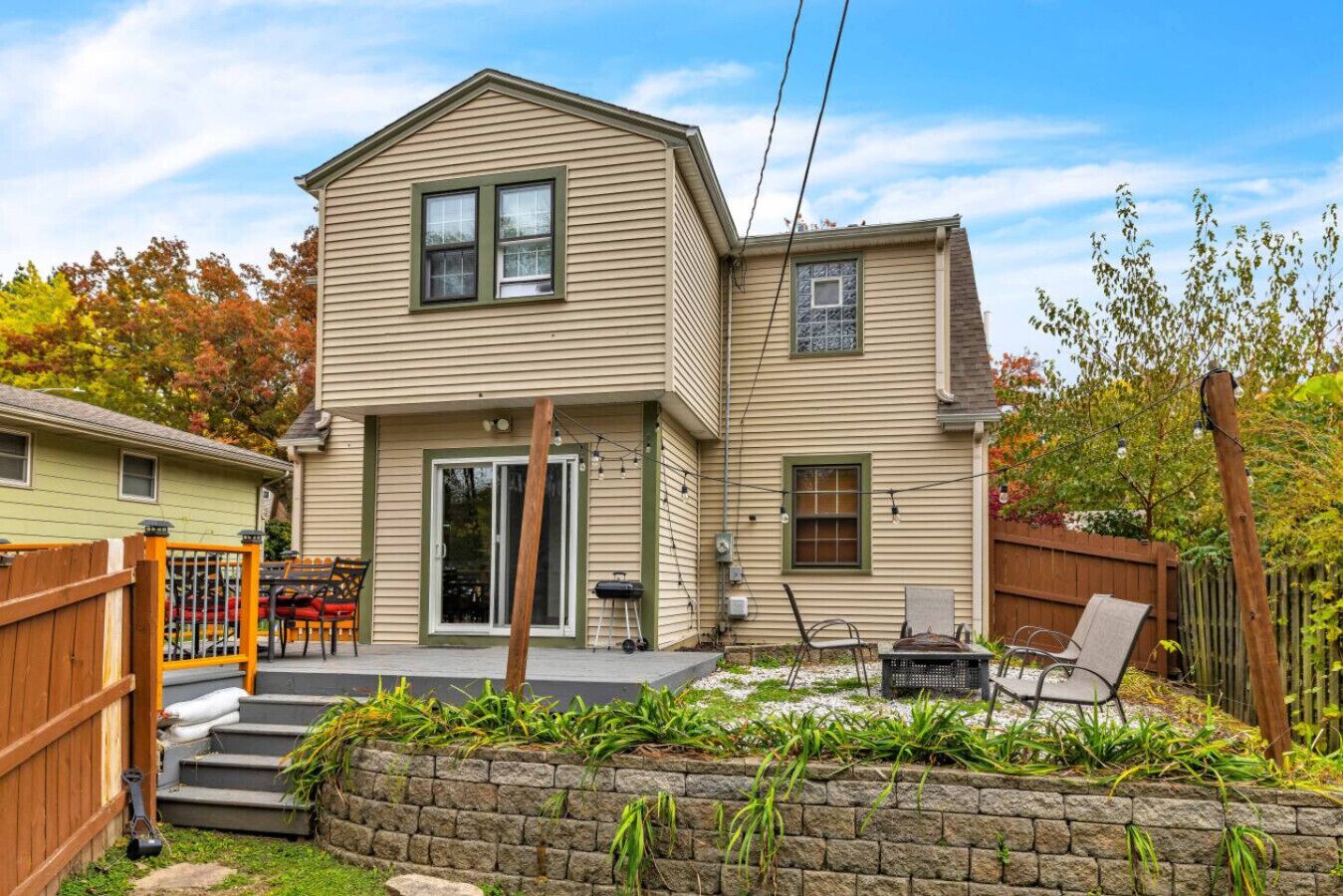 A two-story house with a front porch, a sliding glass door, and a small patio area with outdoor furniture.