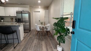 A modern kitchen with a refrigerator, dining table, chairs, and a potted plant. - Modern Stay Near Downtown / Cozy & Clean (San Antonio)