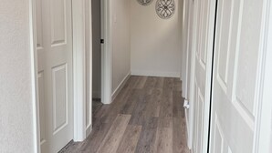 A hallway with white doors, a wooden floor, and a ceiling vent. - Modern Stay Near Downtown / Cozy & Clean (San Antonio)