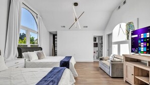 Una camera da letto moderna con due letti, una TV e un pavimento in legno.