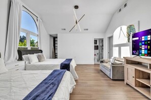 Une chambre moderne avec deux lits, une télévision et un plancher en bois.