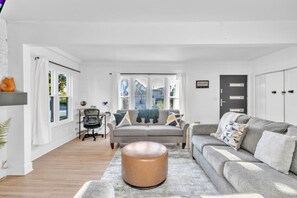 Un salon moderne avec un canapé gris, une table basse ronde et un bureau avec une chaise.