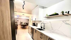 Una cucina moderna con piani in marmo, mobili in legno e una mensola a incasso con piante.