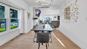 Un'elegante zona pranzo con un tavolo lungo, sedie e un'originale lampada a soffitto dalle forme geometriche.
