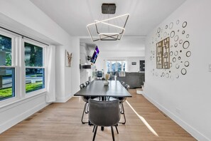 Un espace de salle à manger moderne, avec une longue table, des chaises et un luminaire au plafond au design géométrique original.
