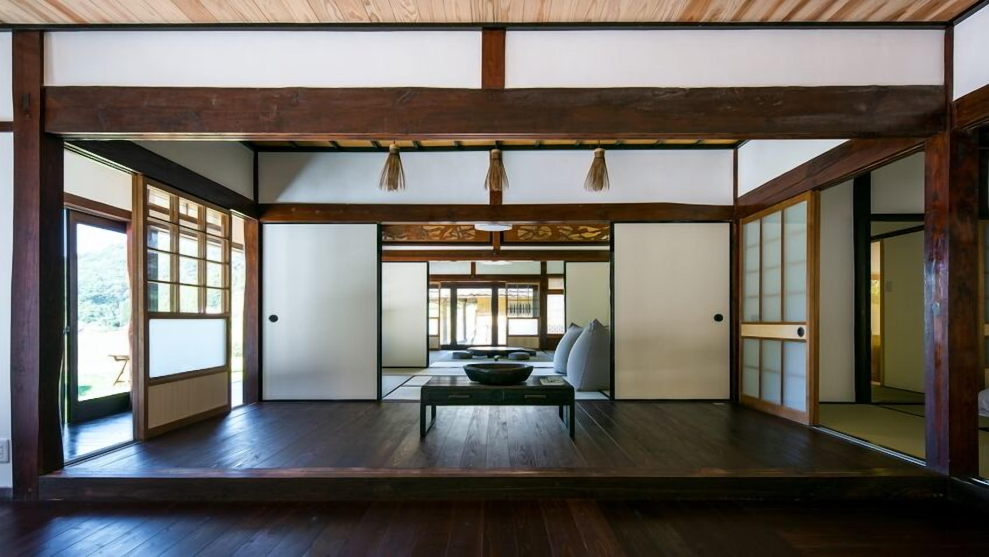 Una habitación japonesa tradicional con suelo de tatami, puertas correderas y una mesa central.