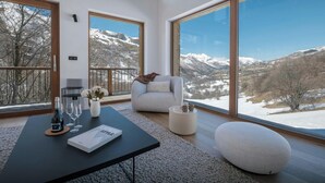 Ein modernes Wohnzimmer mit einer Couch, einem Couchtisch und Blick auf schneebedeckte Berge.