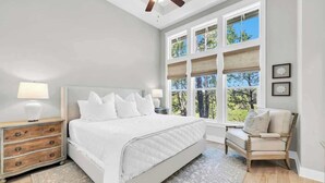 A bedroom with a large bed, a nightstand, a chair, and a window with blinds. - Swaying Palms by Stay on 30a (Inlet Beach)
