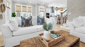 A modern living room with a white sofa, a coffee table, and a kitchen in the background. - Swaying Palms by Stay on 30a (Inlet Beach)