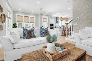 A modern living room with a white sofa, a coffee table, and a kitchen in the background. - Swaying Palms by Stay on 30a (Inlet Beach)