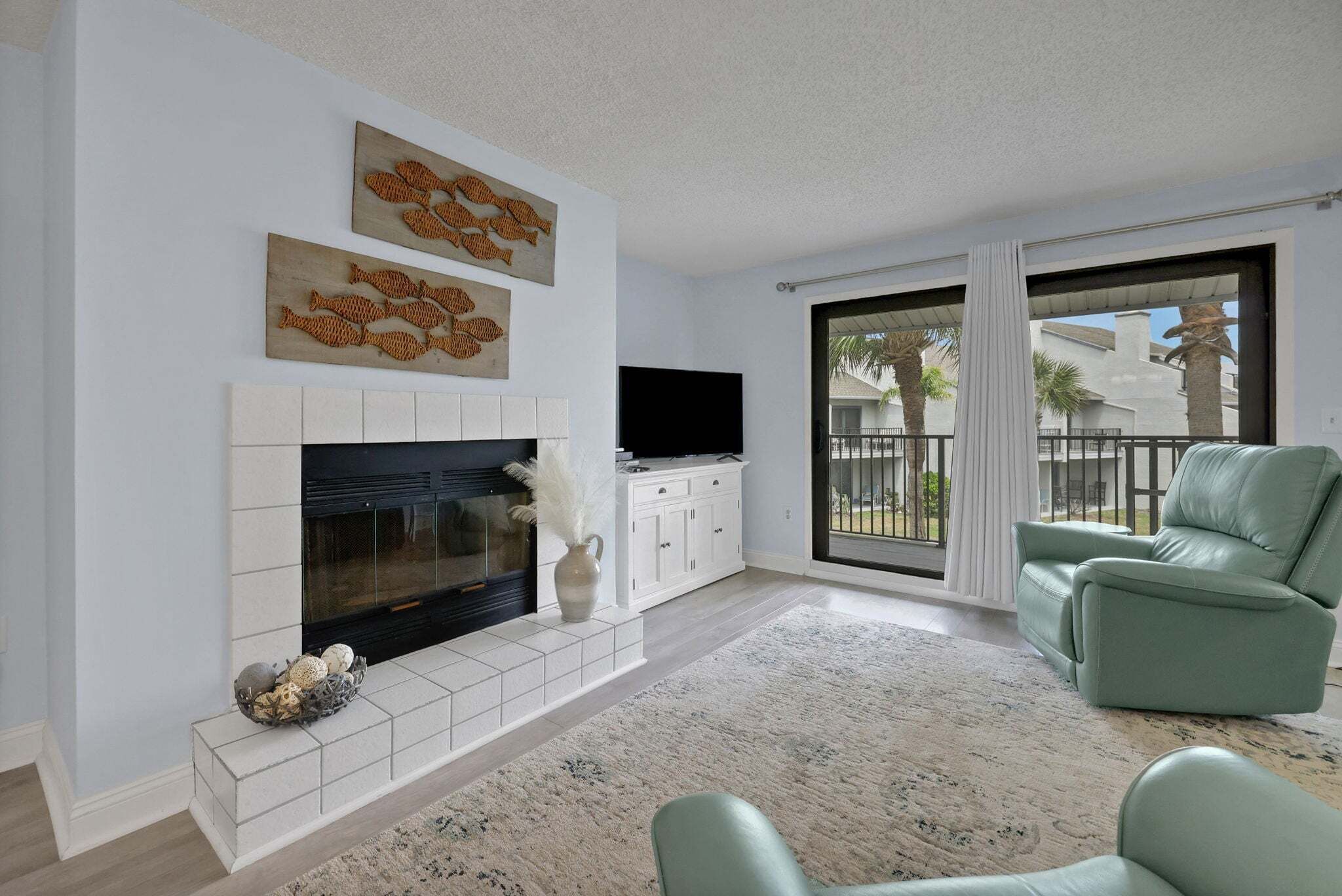 Una sala de estar con chimenea, televisor y sofá verde.