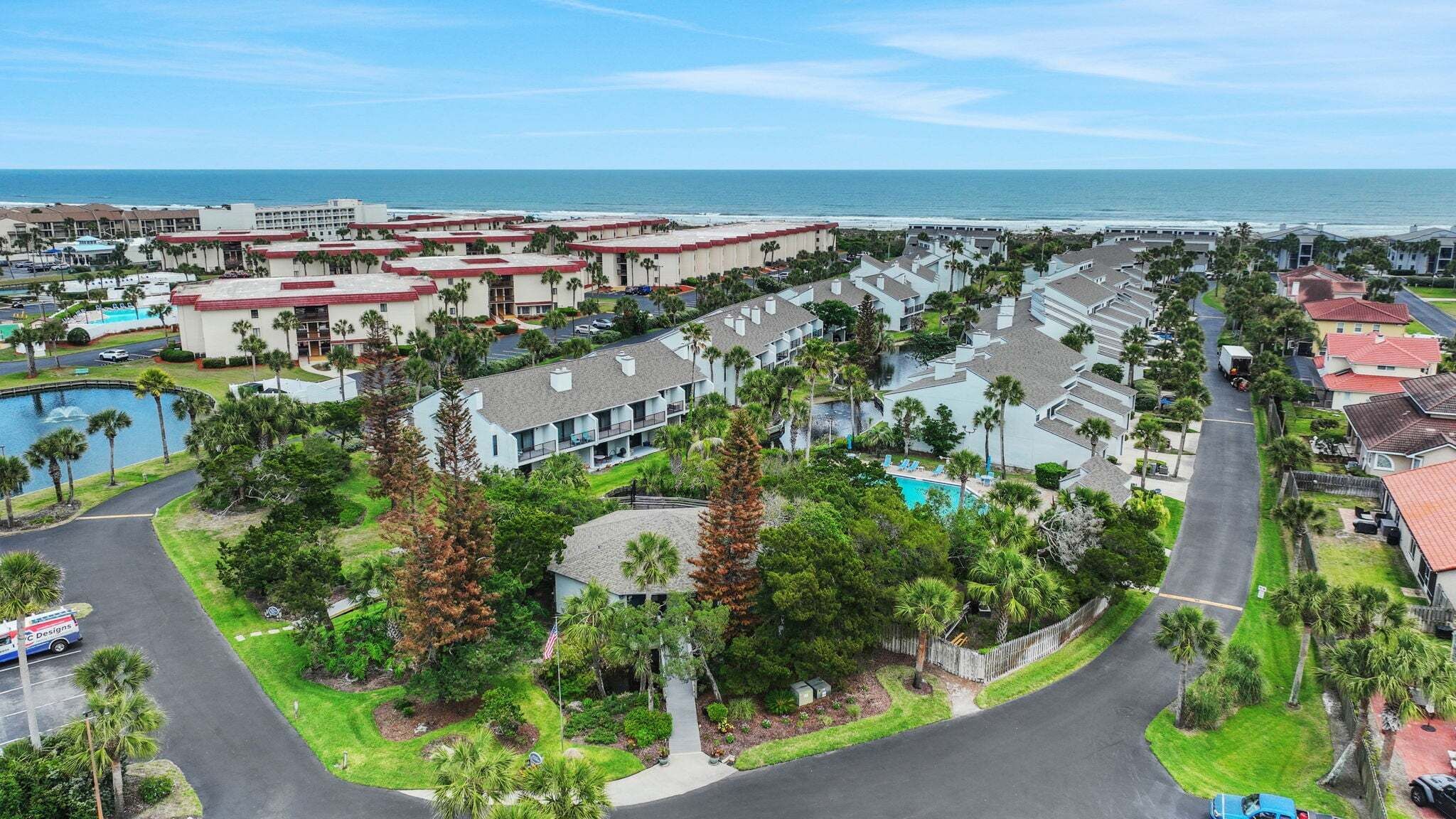 A coastal resort with multiple-story buildings, a swimming pool, and a view of the ocean.