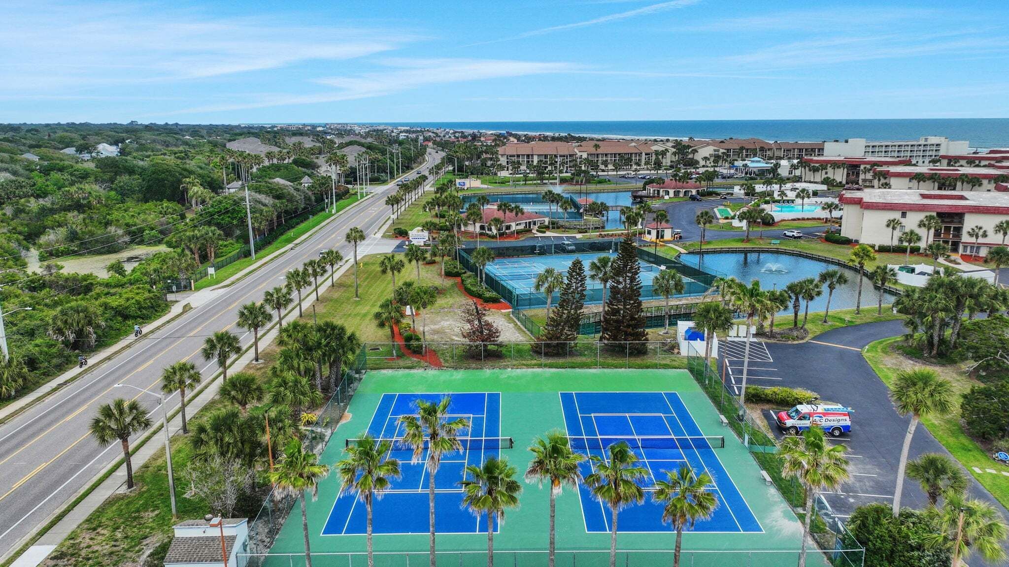 Una cancha de tenis, una piscina y vista al océano.