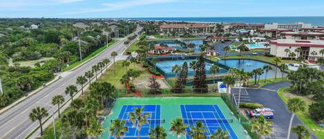 Una cancha de tenis, una piscina y vista al océano.