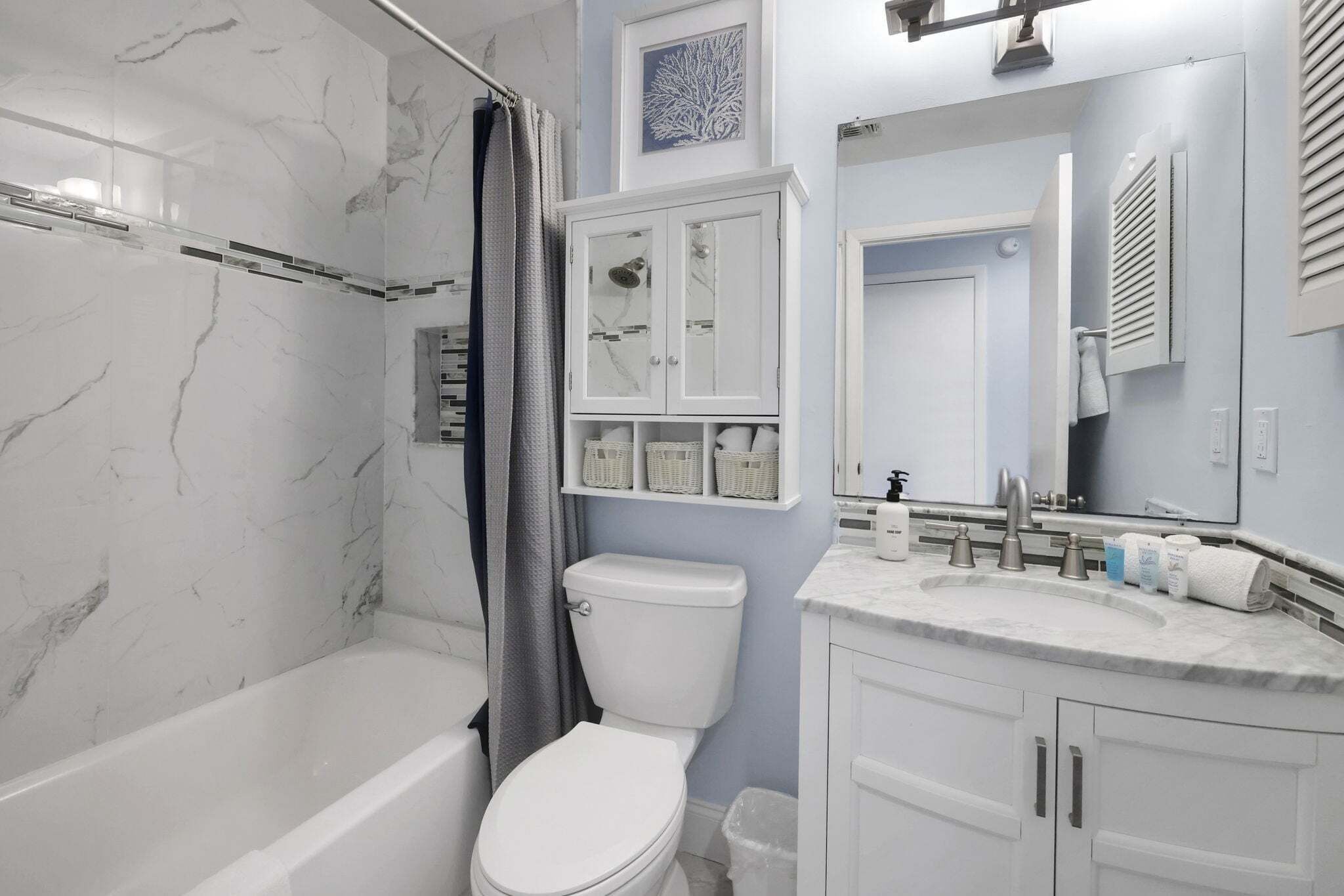 A bathroom with a bathtub, toilet, and vanity with a sink and mirror.