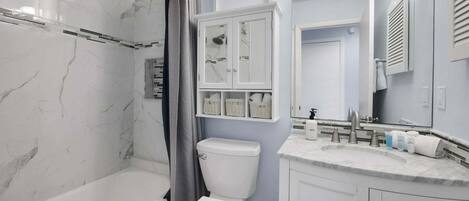 A bathroom with a bathtub, toilet, and vanity with a sink and mirror.
