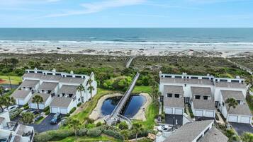Zona residencial costeira com casas modernas, uma ponte e uma praia.