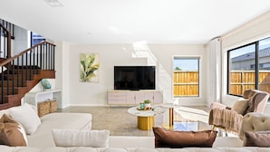 A modern living room with a sofa, coffee table, TV, and a staircase. - Stunning Park-fronted Luxury Grand Family House with Gym, Pool and Spa!!! (Mambourin)