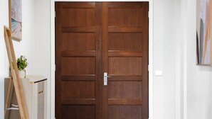 A hallway with a double wooden door, a white wall, and a tiled floor. - Stunning Park-fronted Luxury Grand Family House with Gym, Pool and Spa!!! (Mambourin)