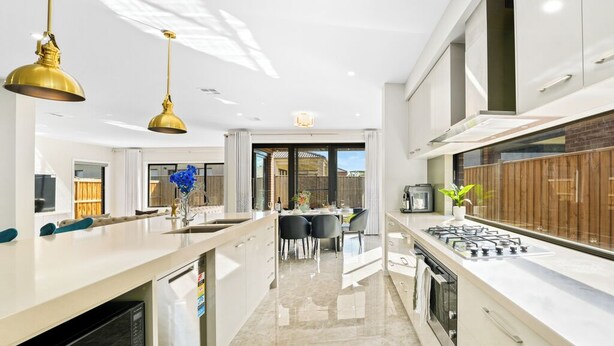 A modern kitchen with a central island, a dining area, and a view of the outdoors. - Stunning Park-fronted Luxury Grand Family House with Gym, Pool and Spa!!! (Mambourin)