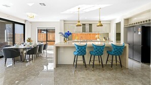 A modern kitchen with a central island, bar stools, and a dining area with a table and chairs. - Stunning Park-fronted Luxury Grand Family House with Gym, Pool and Spa!!! (Mambourin)