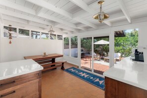 A kitchen with white cabinetry, a wooden bench, and a view to an outdoor patio. - Family Beach House in Pacific Beach | Walk to Beach & Bay (San Diego)