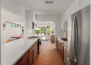Una cocina moderna con armarios blancos, un refrigerador de acero inoxidable y un piso de baldosas hexagonales.