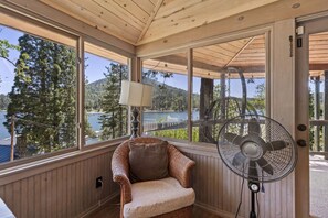 A cozy room with a wicker chair, a standing fan, and a lamp. - Lakeview | Dock Access | Sleeps 16 | Putting Green (Bass Lake)