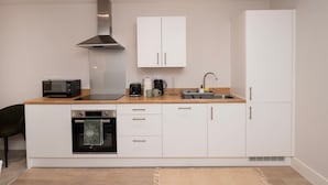 A modern kitchen with white cabinets, a stainless steel range hood, a microwave, a coffee maker, and a sink. - Stylish 1BR Sanctuary in Hull Centre Near Marina (Kingston upon Hull)