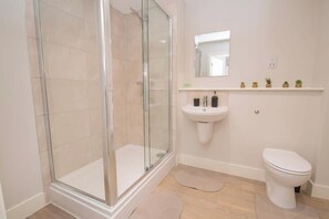Ein modernes Badezimmer mit einer Duschkabine, einem Standwaschbecken und einer Toilette.