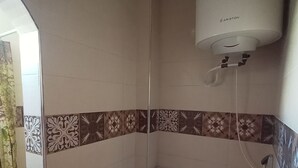 A small bathroom with a toilet, a shower, and a wall-mounted air conditioner. - 2 pretty, quiet rooms a few steps from the Medina (Essaouira)